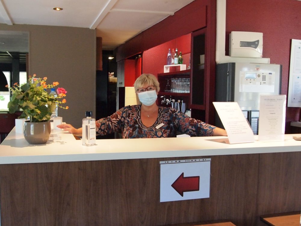 La Directrice vous accueille avec le sourire derrière son masque